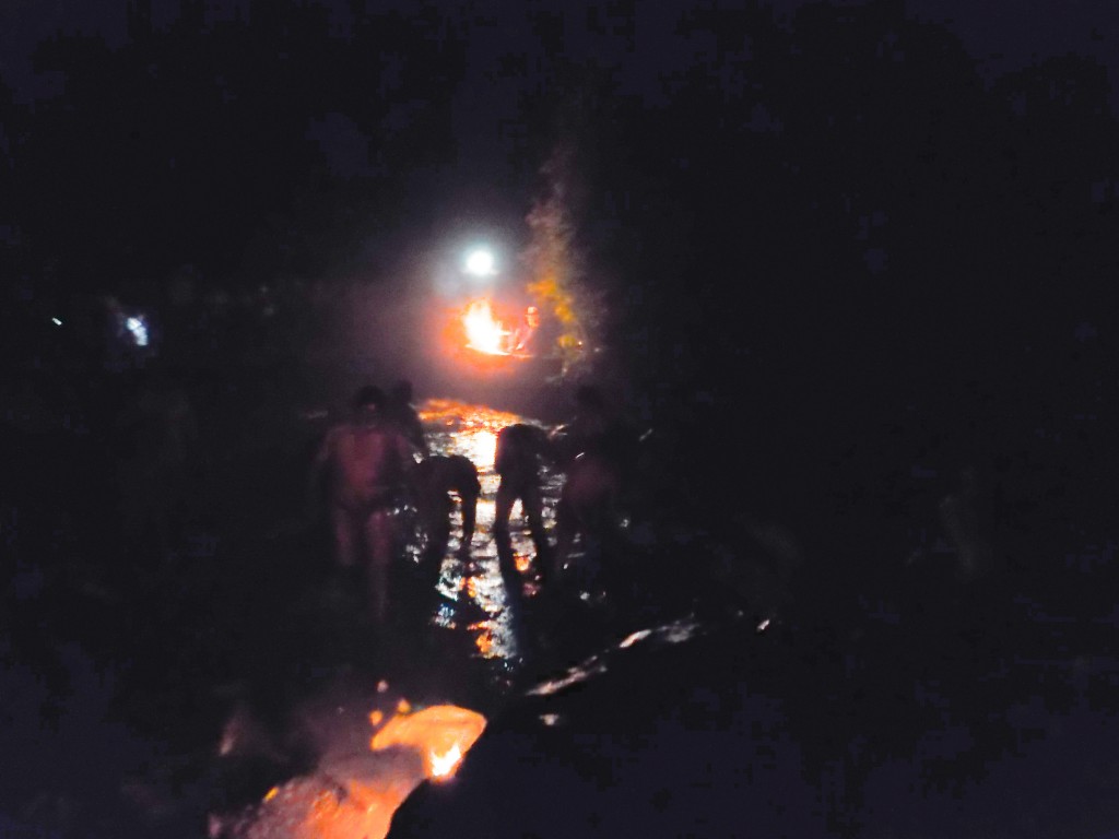 Locals cleansing in the cascada by firelight