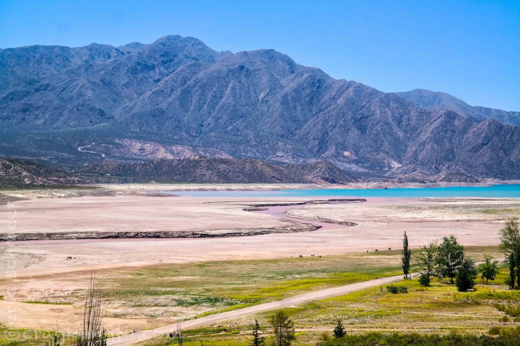 A muddy red river runs into the gorgeous blue waters of Embalse Potrerillos